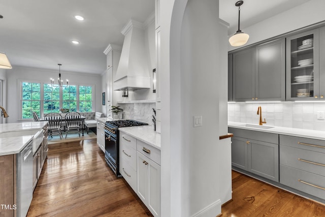 kitchen featuring light stone counters, gas stove, pendant lighting, dark wood-type flooring, and premium range hood