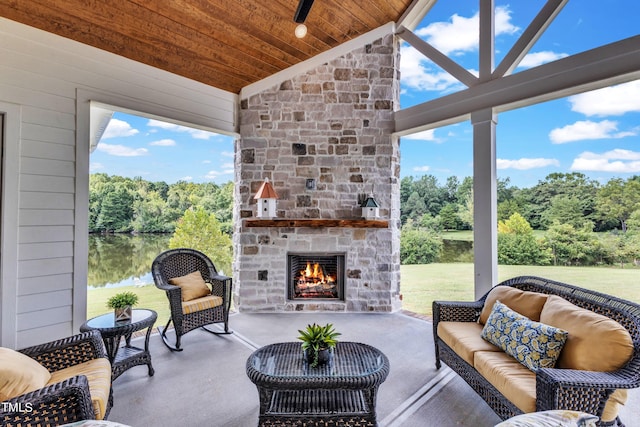 view of patio with an outdoor living space with a fireplace, a water view, and ceiling fan