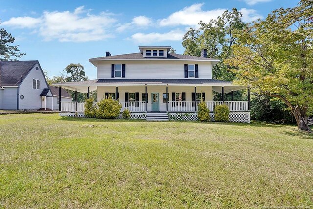 rear view of property featuring a lawn and covered porch