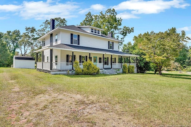 rear view of house with covered porch, a lawn, and a storage unit