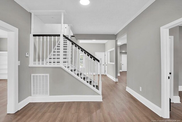 stairs with hardwood / wood-style flooring and crown molding