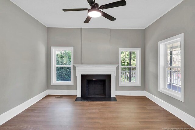 unfurnished living room featuring a wealth of natural light, hardwood / wood-style floors, and ceiling fan