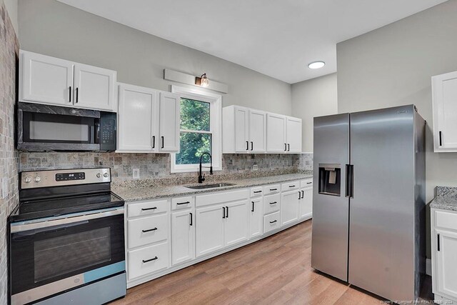 kitchen with appliances with stainless steel finishes, backsplash, sink, and white cabinets