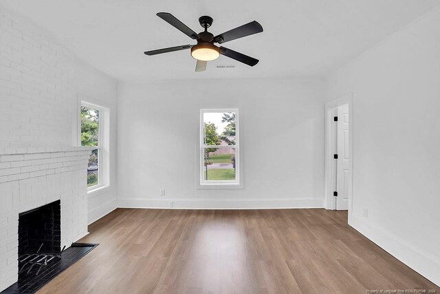 unfurnished living room with wood-type flooring, a brick fireplace, and ceiling fan