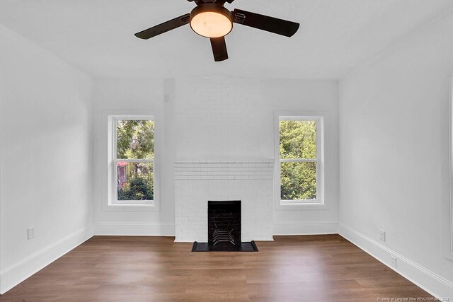 unfurnished living room featuring plenty of natural light, ceiling fan, and dark hardwood / wood-style flooring