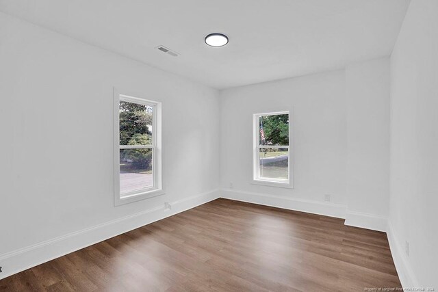 spare room with a healthy amount of sunlight and dark hardwood / wood-style floors