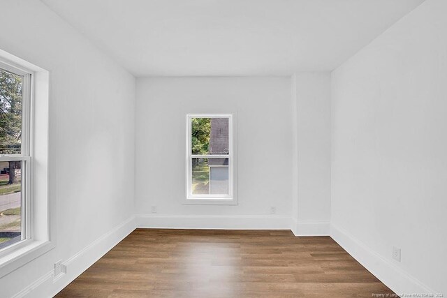 unfurnished room featuring a wealth of natural light and dark hardwood / wood-style flooring