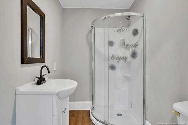 bathroom featuring toilet, wood-type flooring, an enclosed shower, and vanity