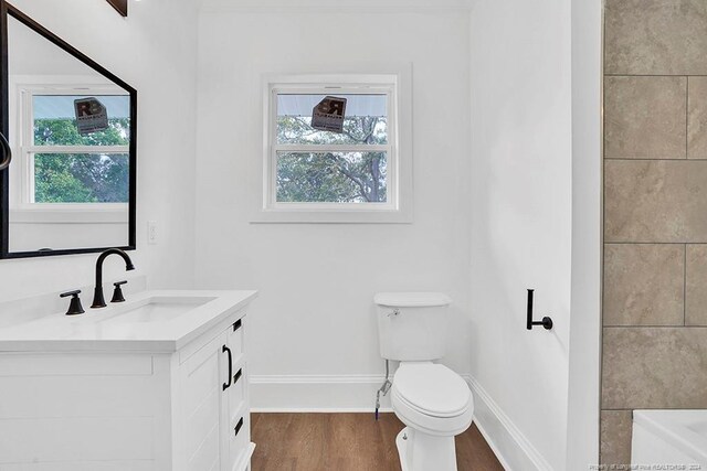 bathroom with vanity, toilet, hardwood / wood-style floors, and a tub