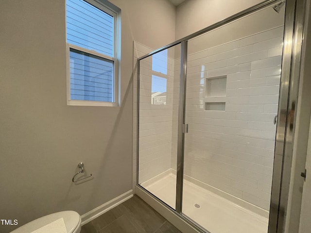 bathroom with a shower with shower door and toilet