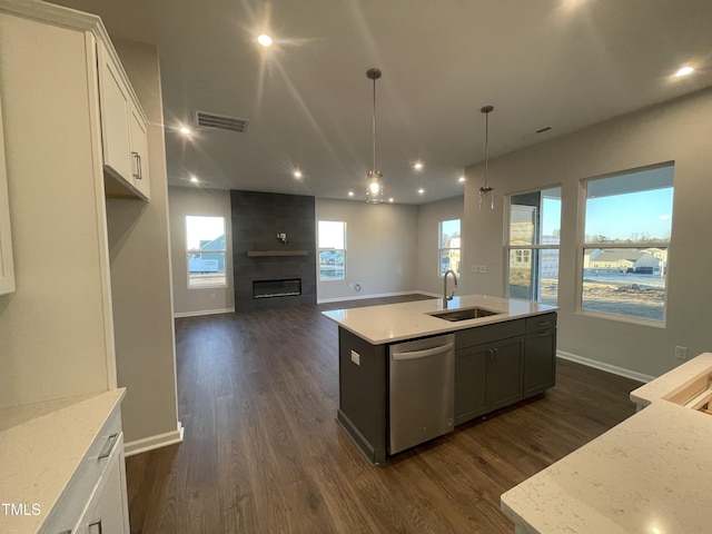 kitchen with white cabinetry, sink, hanging light fixtures, stainless steel dishwasher, and an island with sink