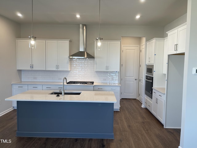 kitchen featuring pendant lighting, wall chimney exhaust hood, white cabinetry, and appliances with stainless steel finishes