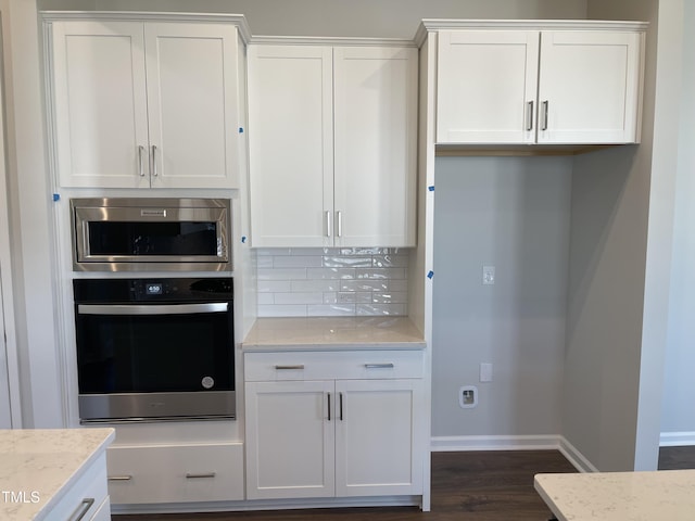 kitchen with decorative backsplash, stainless steel appliances, and white cabinetry