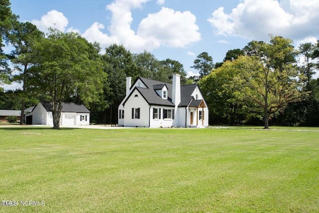 view of front of property with a chimney, a front yard, and an outdoor structure