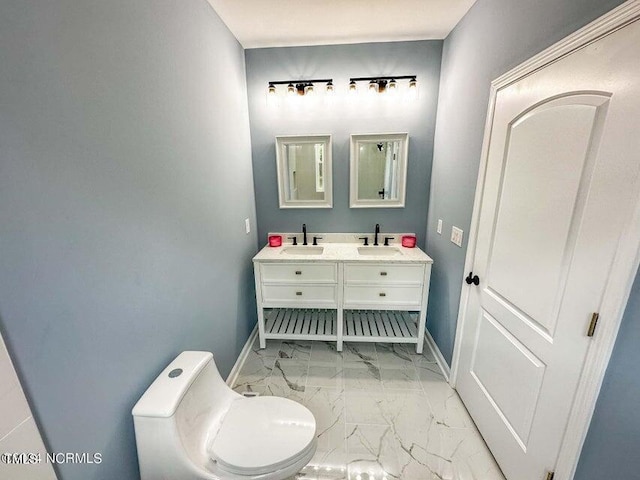 bathroom with double vanity, baseboards, marble finish floor, and a sink