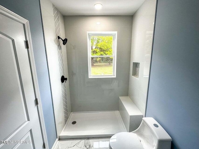 bathroom featuring a shower stall, toilet, and marble finish floor