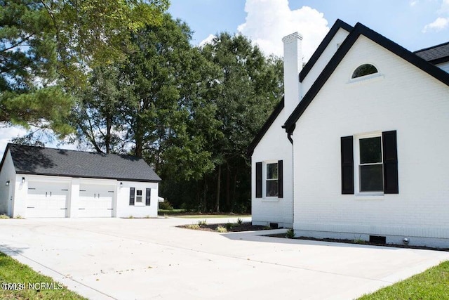 view of side of property featuring brick siding, crawl space, driveway, and a chimney