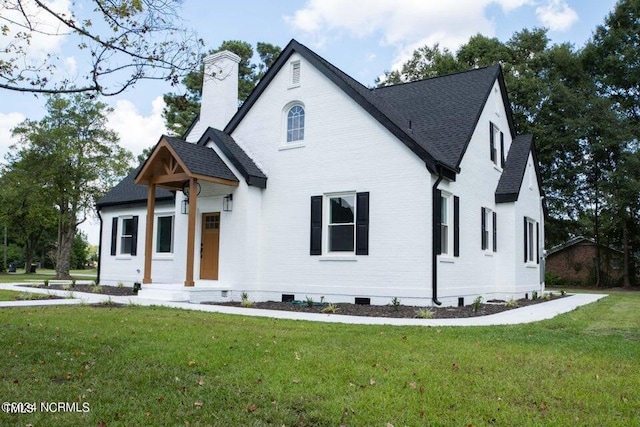 modern farmhouse with brick siding, a front yard, roof with shingles, a chimney, and crawl space