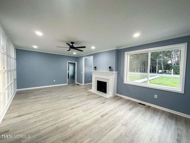 unfurnished living room with wood finished floors, crown molding, a fireplace, and baseboards