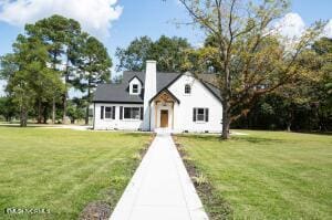 view of front of property featuring a chimney and a front yard