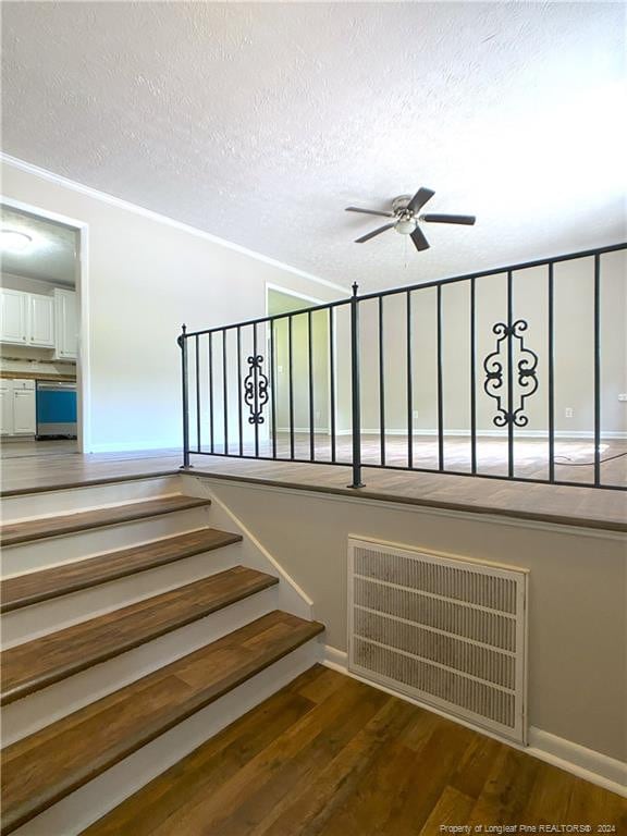 staircase with a textured ceiling, wood-type flooring, ceiling fan, and a wealth of natural light