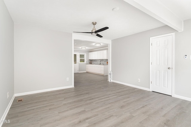 unfurnished living room featuring light hardwood / wood-style flooring, beamed ceiling, and ceiling fan