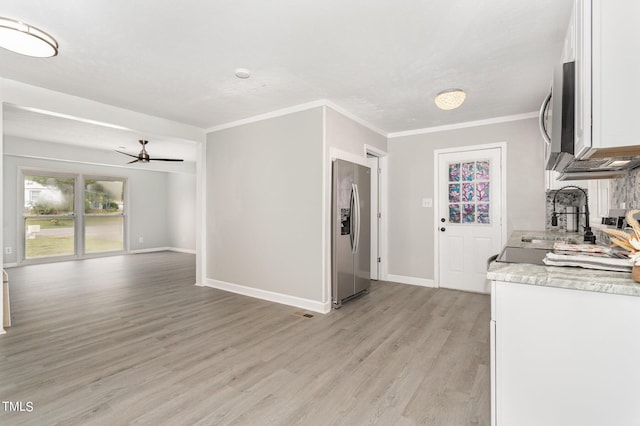 kitchen with stainless steel appliances, light wood-style floors, white cabinets, crown molding, and baseboards