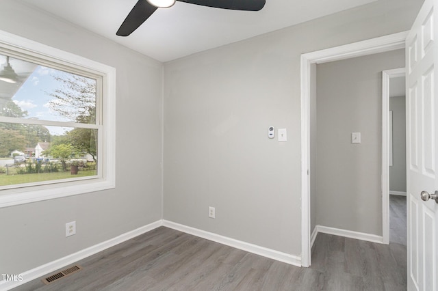 unfurnished room with a ceiling fan, wood finished floors, baseboards, and visible vents