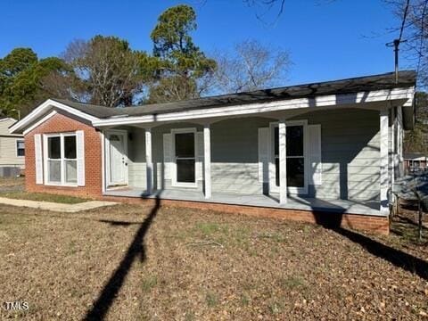 rear view of house with a lawn and a porch