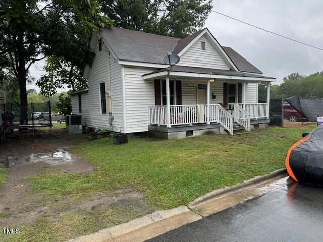 view of front of house featuring cooling unit, a front lawn, and a porch