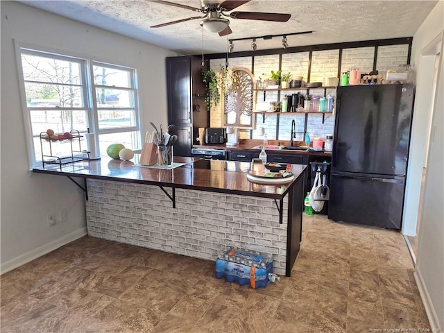 kitchen with sink, rail lighting, ceiling fan, a textured ceiling, and black fridge