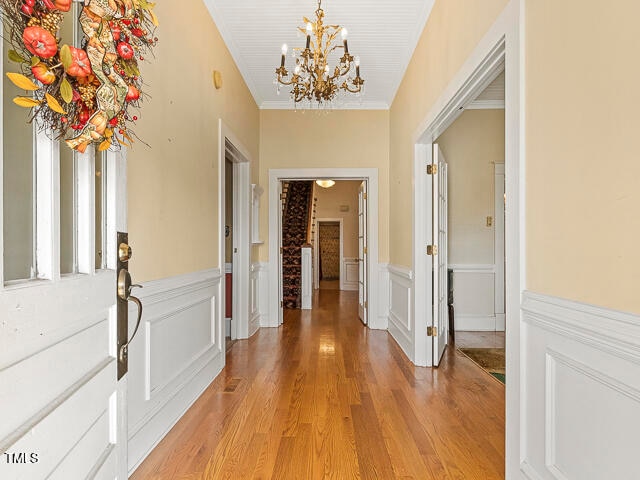 corridor with a notable chandelier, light hardwood / wood-style floors, and crown molding