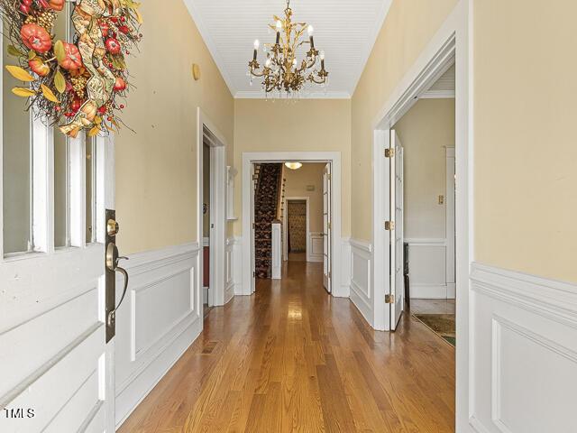 715 E Broad St, Fuquay Varina, NC 27526 - corridor with a chandelier, light wood-style flooring, wainscoting, ornamental molding, and a decorative wall