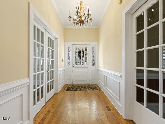 715 E Broad St, Fuquay Varina, NC 27526 - doorway with a chandelier, wood finished floors, a decorative wall, crown molding, and wainscoting