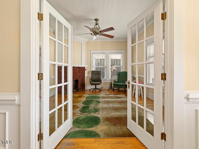 sunroom featuring french doors, ceiling fan, and a fireplace