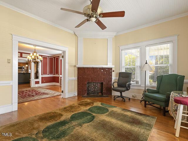715 E Broad St, Fuquay Varina, NC 27526 - sitting room featuring ornamental molding, a fireplace, a chandelier, a ceiling fan, and wood finished floors
