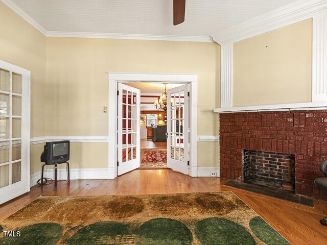 715 E Broad St, Fuquay Varina, NC 27526 - unfurnished living room with ornamental molding, wood finished floors, french doors, a chandelier, and a ceiling fan