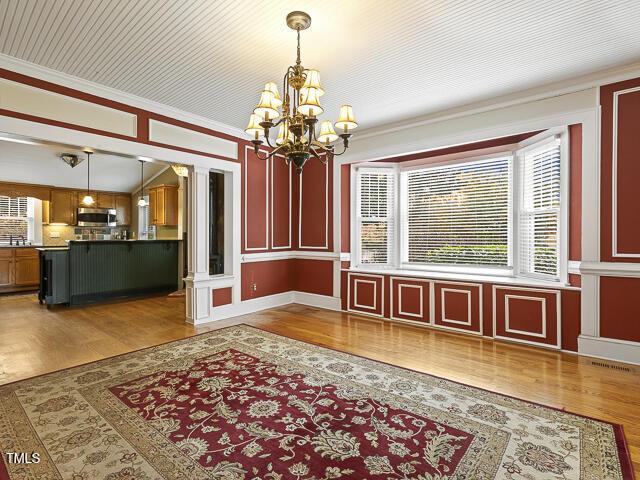 715 E Broad St, Fuquay Varina, NC 27526 - unfurnished dining area featuring a chandelier, wood finished floors, and ornamental molding