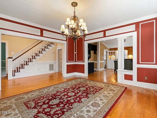 interior space featuring ornamental molding, wood-type flooring, and ornate columns