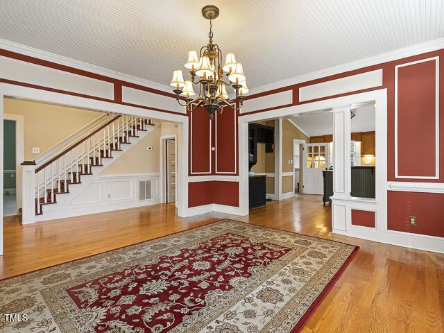 715 E Broad St, Fuquay Varina, NC 27526 - entrance foyer featuring wood finished floors, a chandelier, stairway, a decorative wall, and crown molding