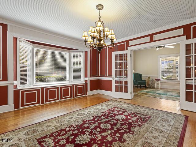 715 E Broad St, Fuquay Varina, NC 27526 - unfurnished dining area featuring french doors, a chandelier, ornamental molding, wood finished floors, and a decorative wall