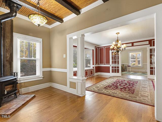 715 E Broad St, Fuquay Varina, NC 27526 - foyer featuring a wood stove, wood finished floors, beamed ceiling, a chandelier, and ornate columns