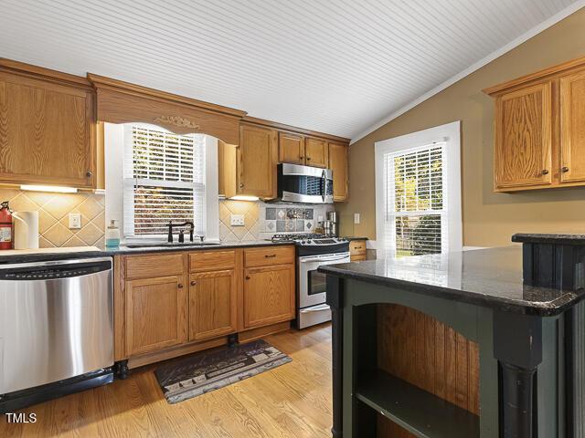715 E Broad St, Fuquay Varina, NC 27526 - kitchen with appliances with stainless steel finishes, a sink, vaulted ceiling, backsplash, and light wood-type flooring