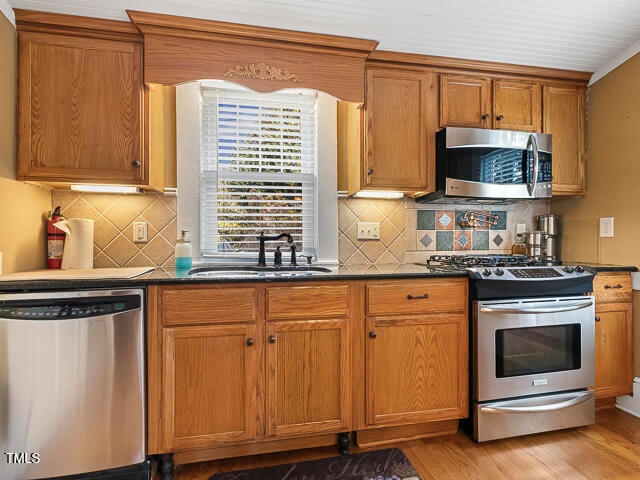 kitchen with light hardwood / wood-style flooring, backsplash, sink, and stainless steel appliances