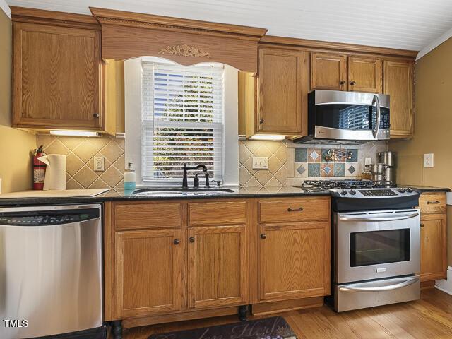 715 E Broad St, Fuquay Varina, NC 27526 - kitchen featuring stainless steel appliances, dark countertops, a sink, and light wood-style floors