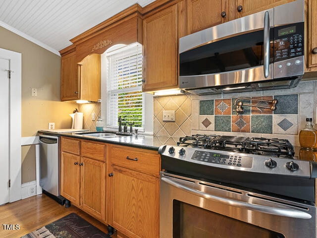 kitchen with ornamental molding, backsplash, appliances with stainless steel finishes, dark hardwood / wood-style floors, and sink