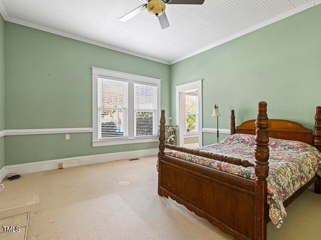 bedroom featuring ornamental molding, light carpet, and ceiling fan