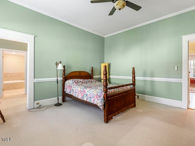 bedroom featuring ensuite bathroom, light carpet, ceiling fan, and crown molding