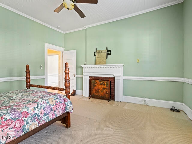 carpeted bedroom featuring ornamental molding and ceiling fan