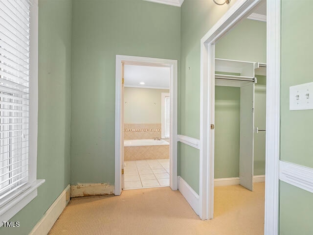 hallway with light carpet and crown molding